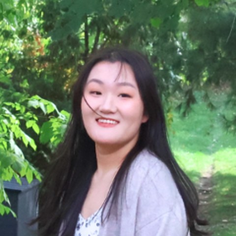 Portrait of Bella Chen smiling outdoors among green trees
