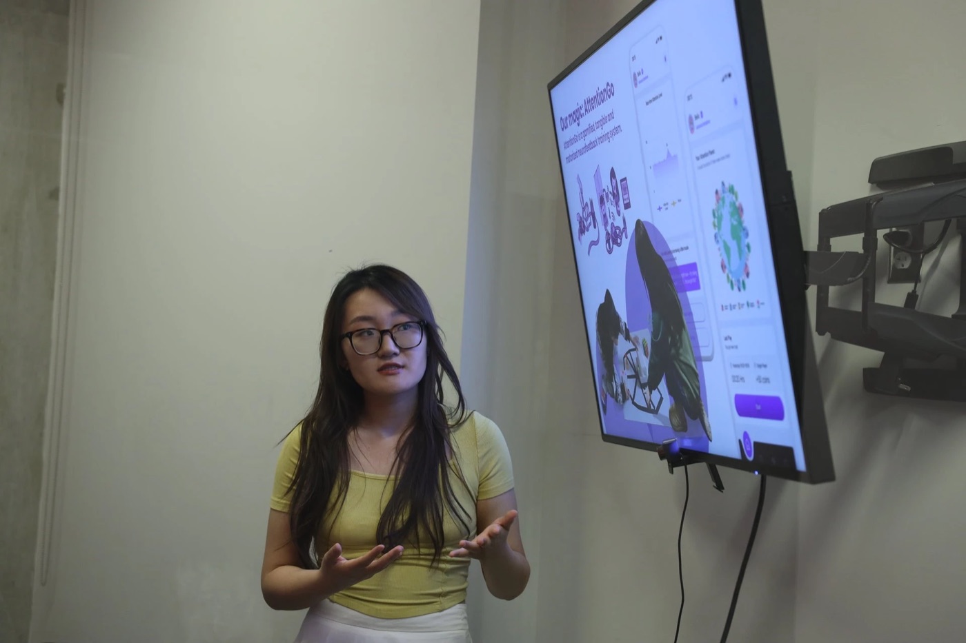 Bella Chen presenting AttentionGo in front of a screen showing the pitch deck